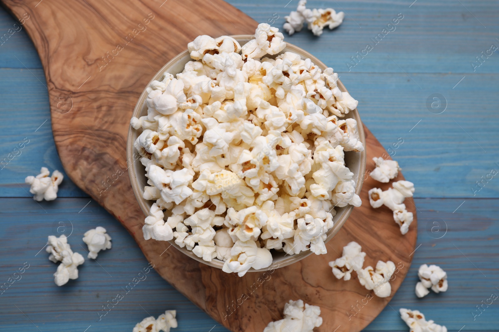 Photo of Tasty popcorn on light blue wooden table, flat lay