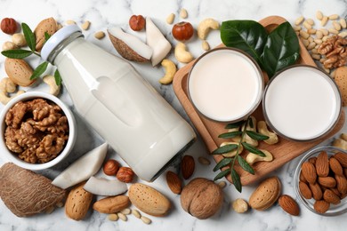 Photo of Vegan milk and different nuts on white marble table, flat lay