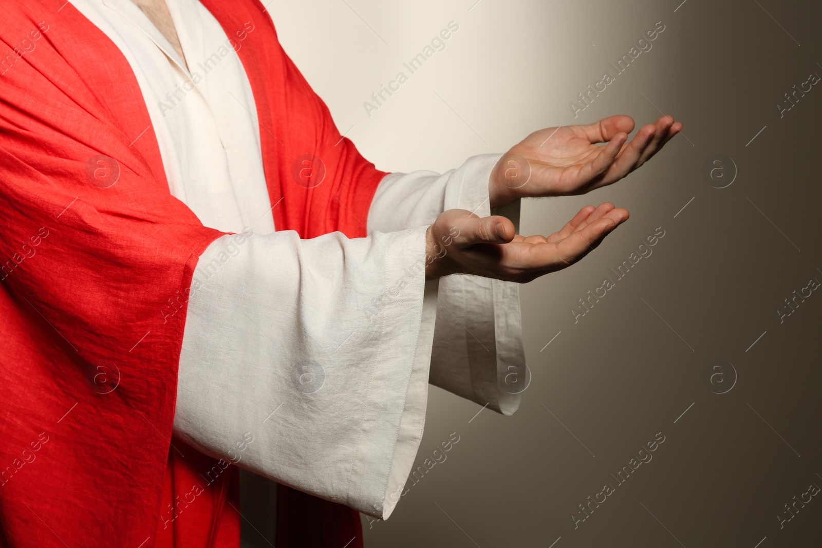 Photo of Jesus Christ reaching out his hands on beige background, closeup