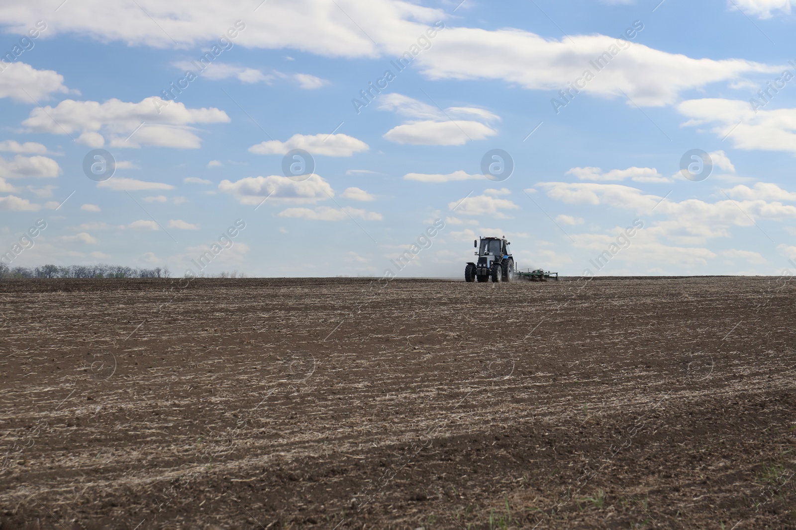 Photo of Tractor with planter cultivating field on sunny day. Agricultural industry