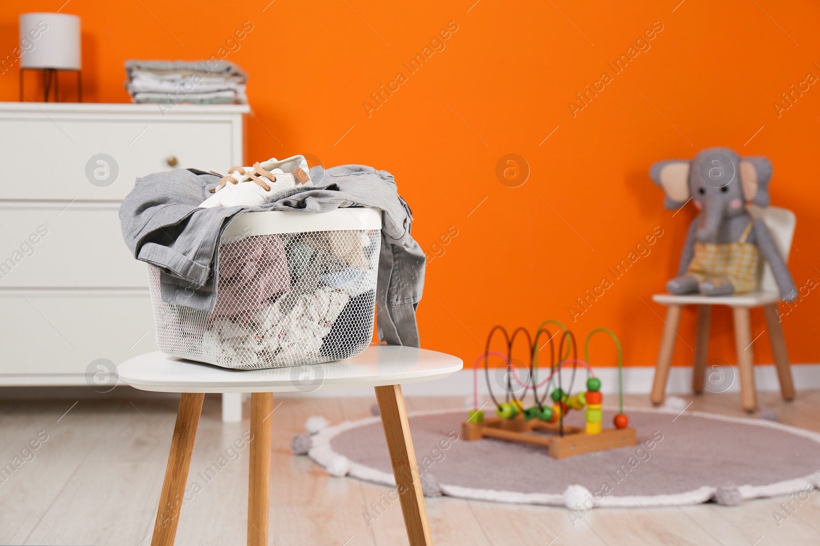 Photo of Laundry basket with baby clothes on white wooden table in child room, space for text