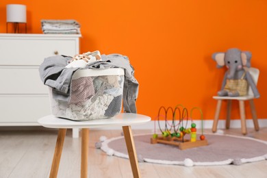 Photo of Laundry basket with baby clothes on white wooden table in child room, space for text