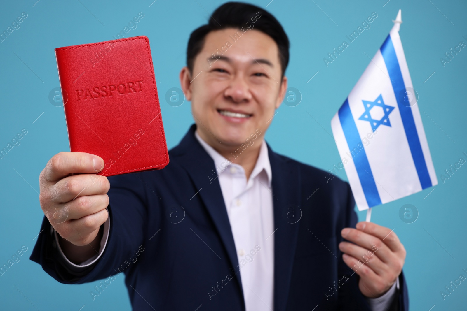 Photo of Immigration. Happy man with passport and flag of Israel on light blue background, selective focus