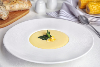 Photo of Delicious corn cream soup served on white table