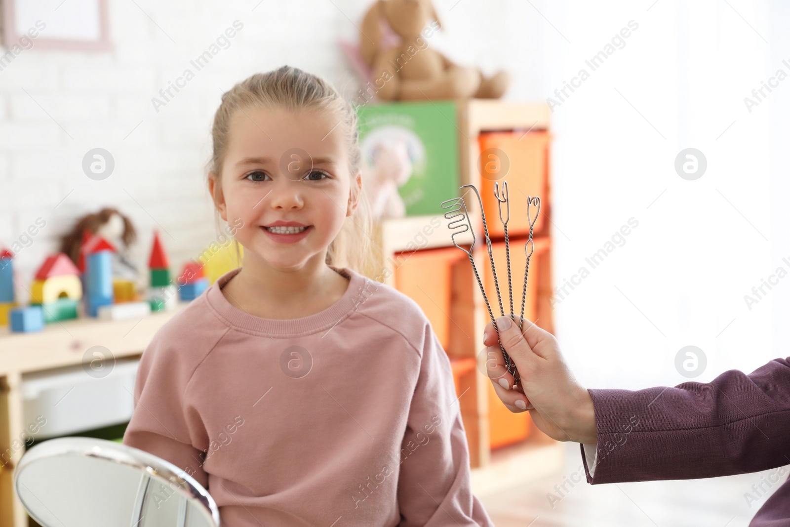 Photo of Speech therapist using logopedic probes on session with little girl in office