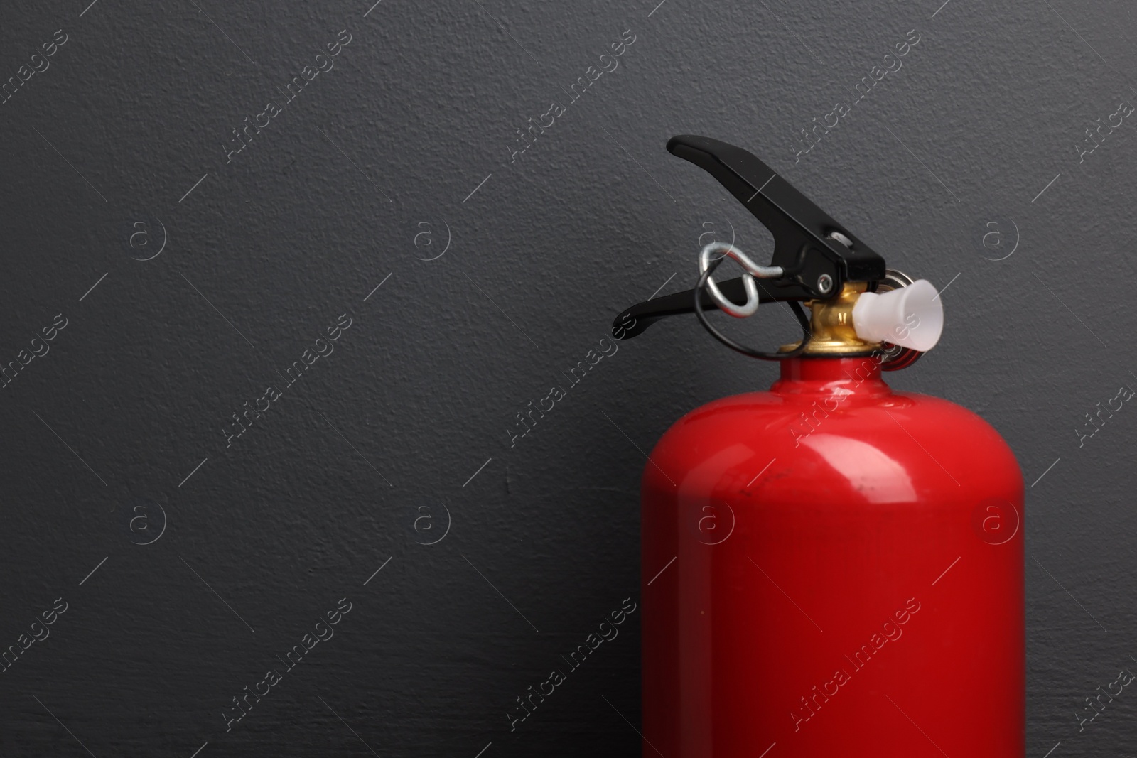 Photo of One fire extinguisher near grey wall, space for text