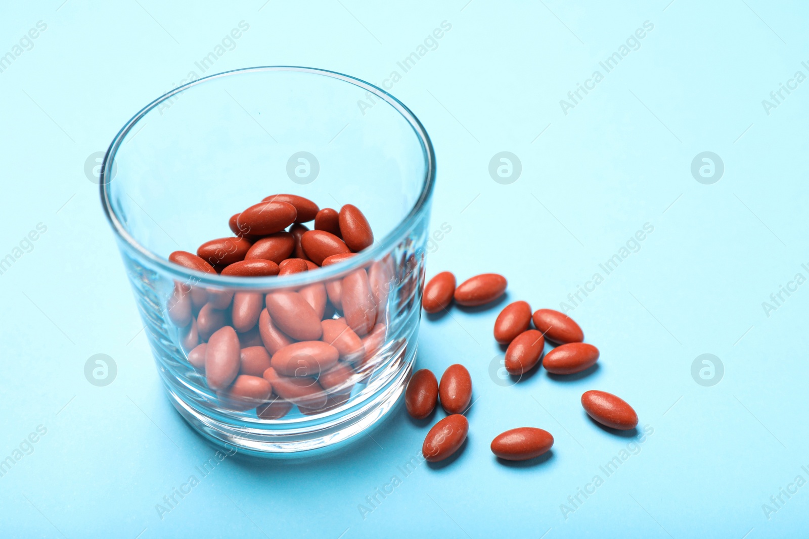 Photo of Glass with pills on turquoise background, closeup. Anemia treatment