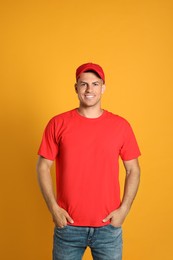 Photo of Happy man in red cap and tshirt on yellow background. Mockup for design