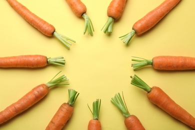 Flat lay composition with fresh carrots on color background. Space for text