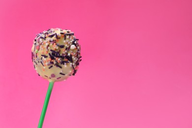 Photo of Delicious confectionery. Sweet cake pop decorated with sprinkles on pink background, closeup. Space for text