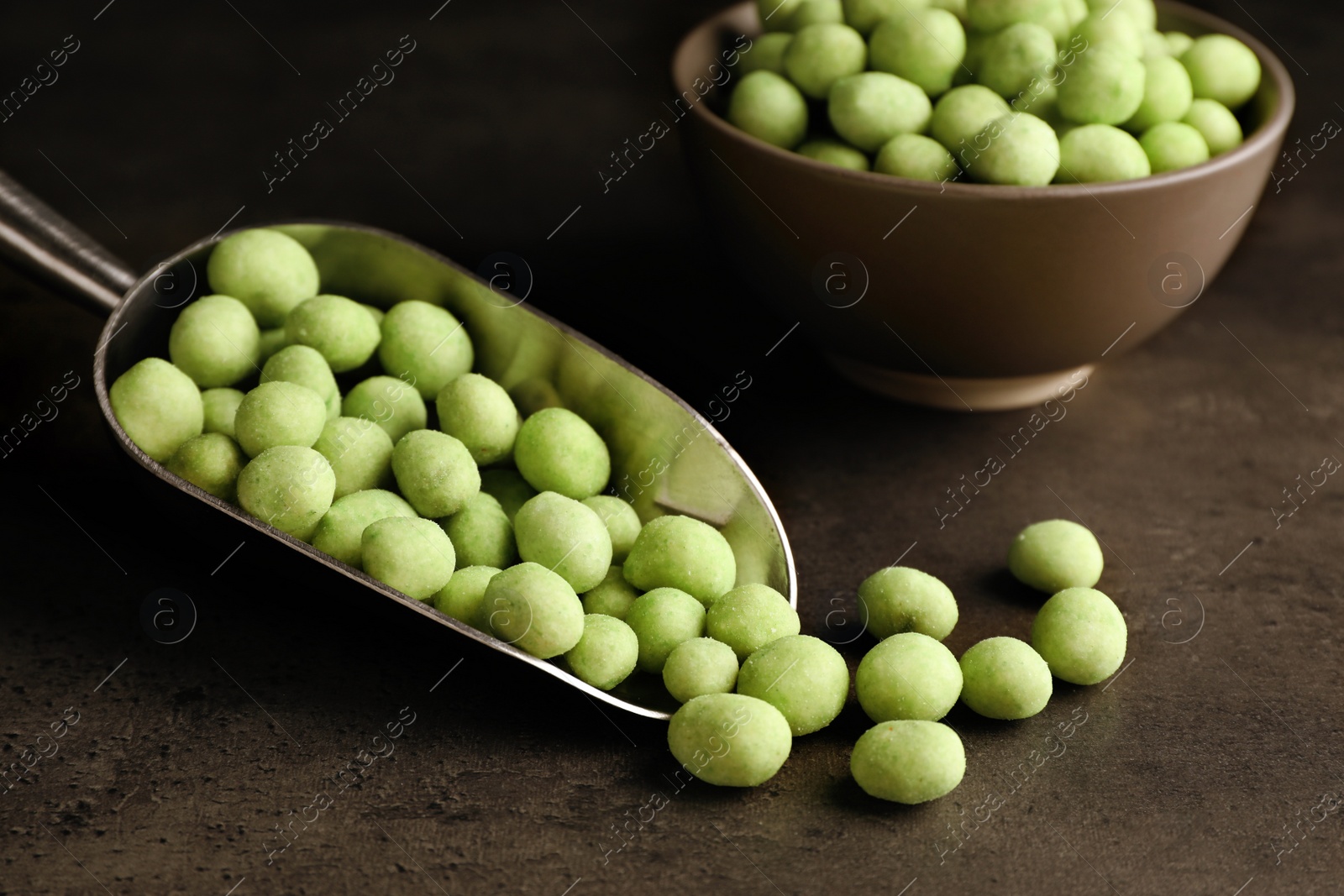 Photo of Tasty wasabi coated peanuts on grey table, closeup