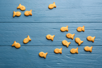 Delicious goldfish crackers on blue wooden table, flat lay