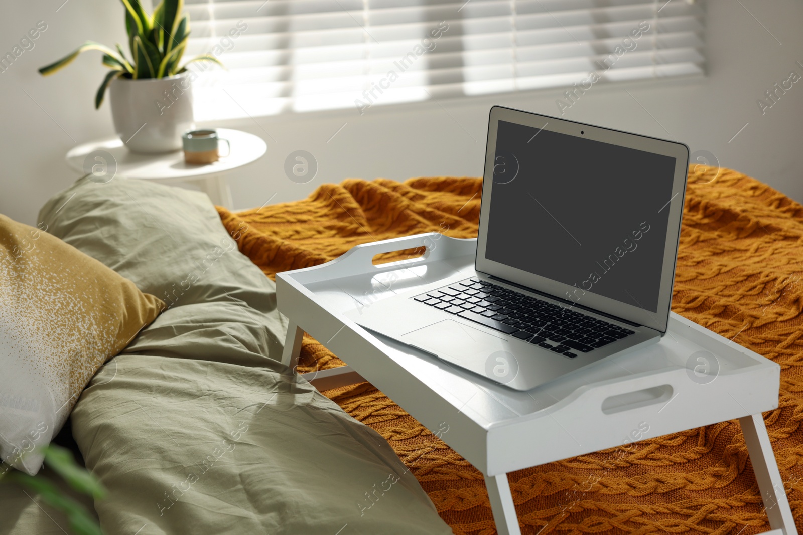 Photo of White tray with modern laptop on bed indoors