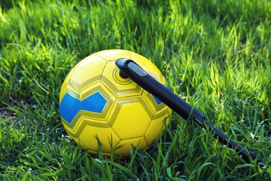 Photo of Soccer ball with manual pump inflator on green grass