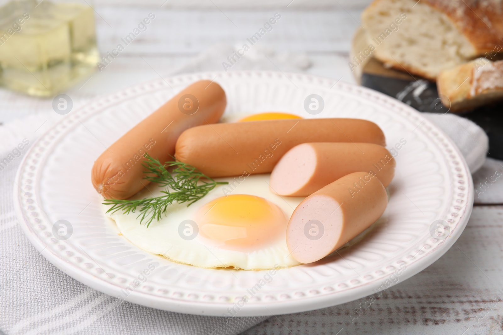 Photo of Delicious boiled sausages, fried eggs and dill on wooden table, closeup