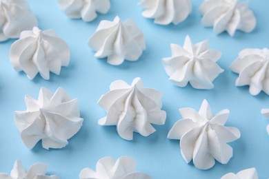 Photo of Tasty meringue cookies on light blue background, closeup