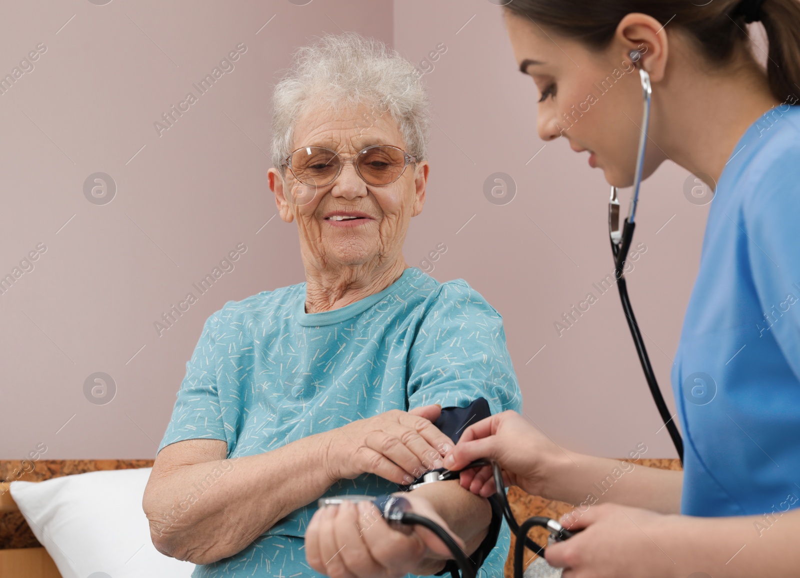 Photo of Nurse measuring senior woman's blood pressure in hospital ward. Medical assisting