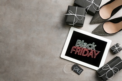 Photo of Tablet with Black Friday announcement, shoes and gifts on grey background, flat lay. Space for text