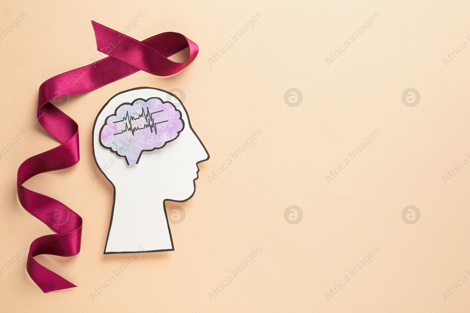 Photo of Human head cutout with brain near purple ribbon on beige background, flat lay. Epilepsy awareness