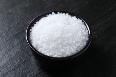 Photo of Organic white salt in bowl on black table