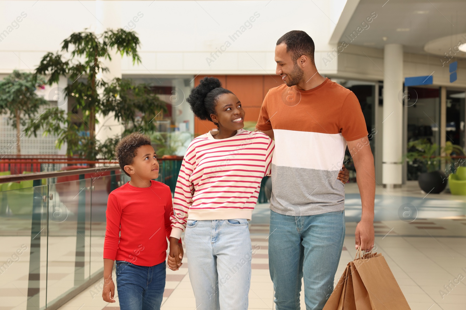 Photo of Family shopping. Happy parents and son with purchases in mall