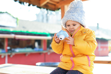 Photo of Cute little photographer with toy camera outdoors