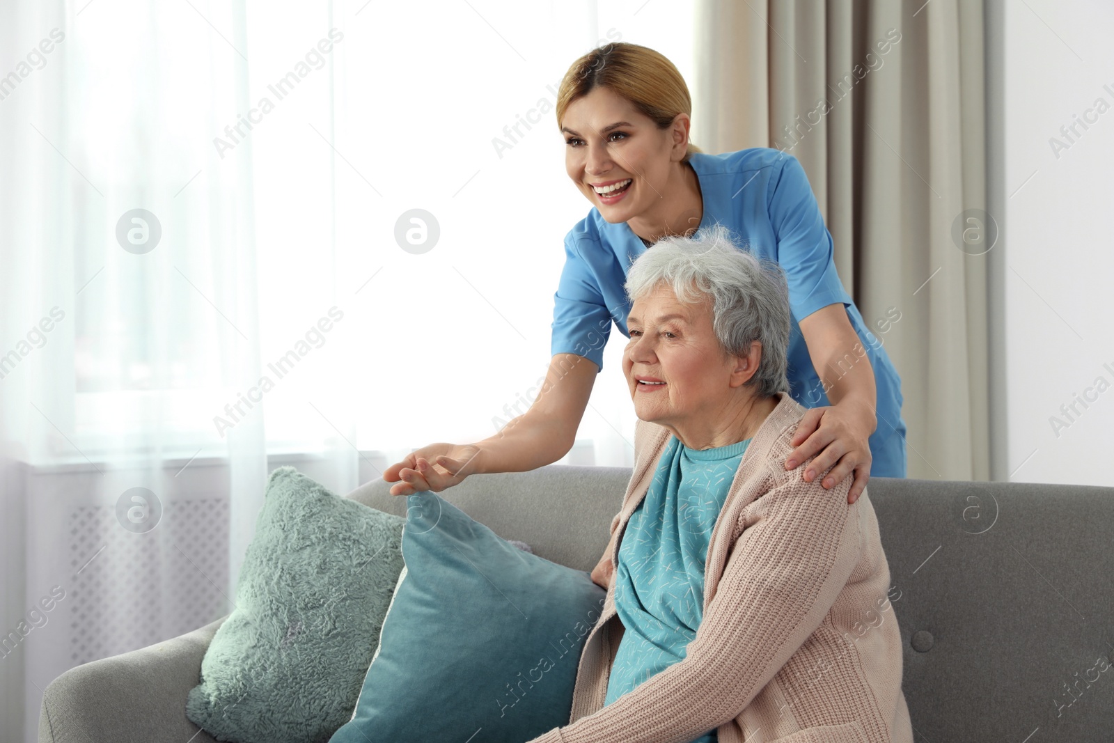 Photo of Nurse with elderly woman indoors, space for text. Assisting senior people