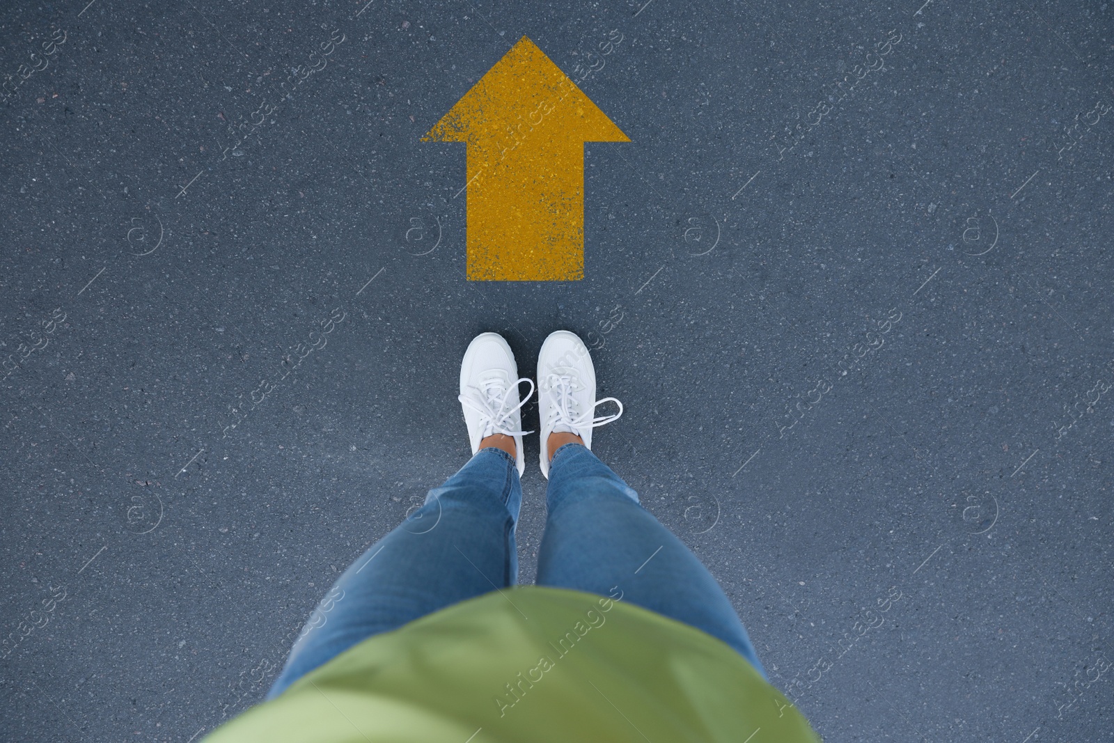 Image of Planning future. Woman standing in front of drawn mark on road, closeup. Yellow arrow showing direction of way