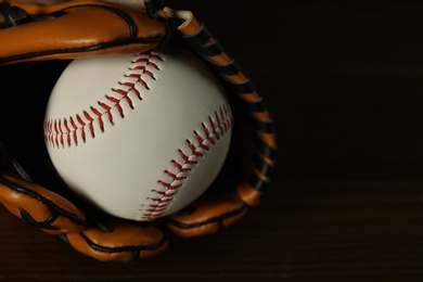 Leather baseball ball and glove on wooden table, closeup