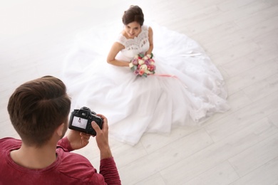 Professional photographer taking photo of beautiful bride in studio