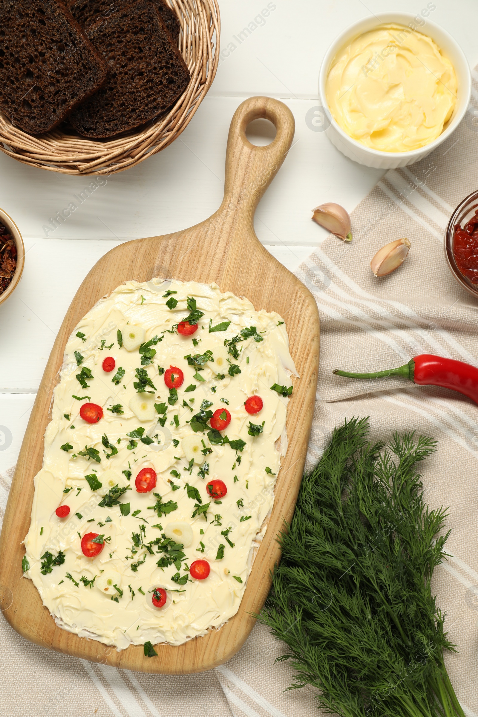 Photo of Fresh natural butter board with ingredients and bread on white wooden table, flat lay