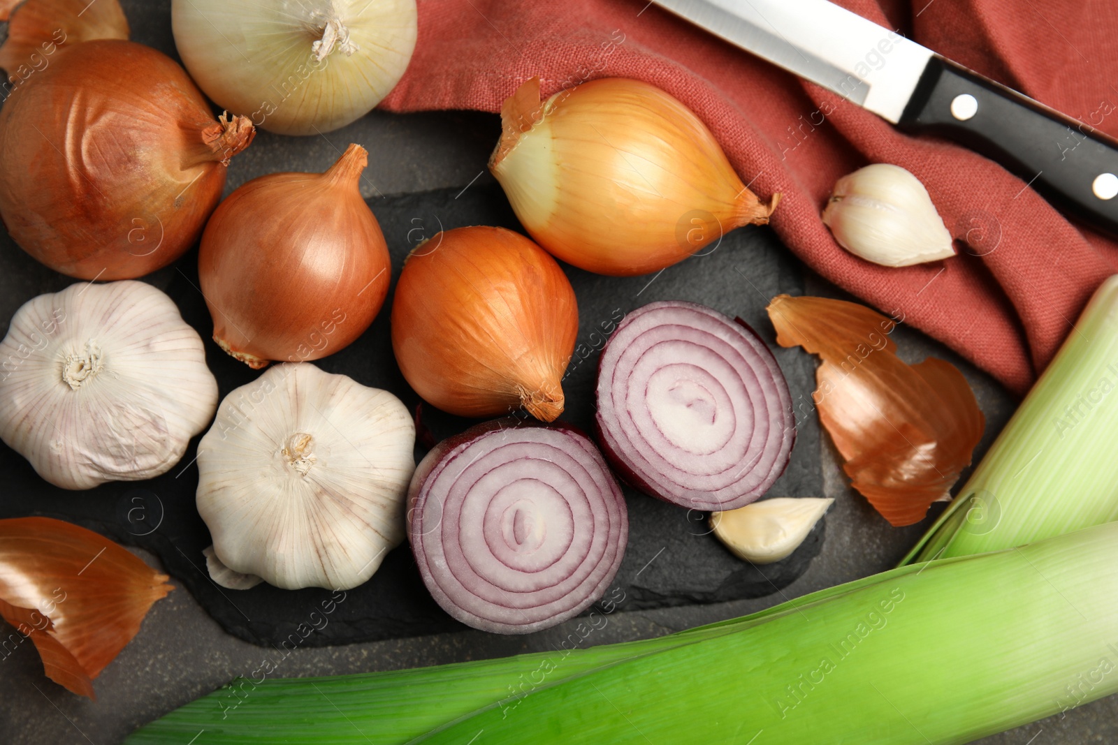 Photo of Fresh whole and cut onions, leeks, garlic on grey table, flat lay