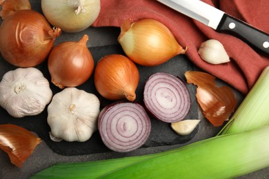 Photo of Fresh whole and cut onions, leeks, garlic on grey table, flat lay