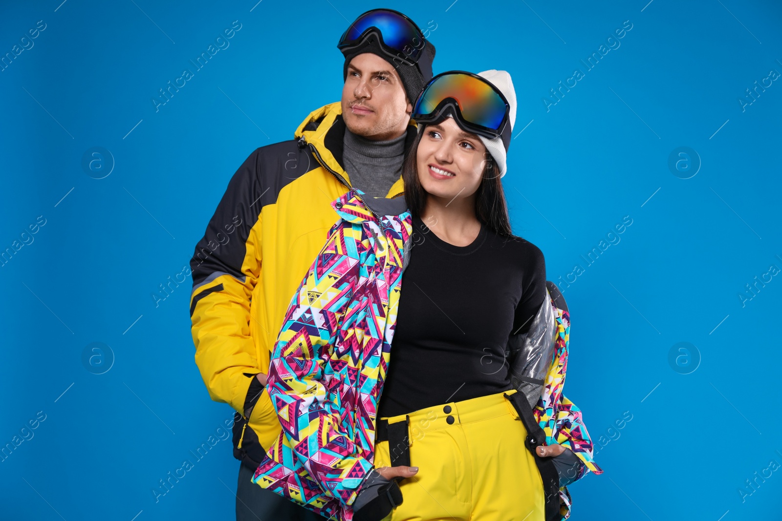 Photo of Couple wearing stylish winter sport clothes on light blue background