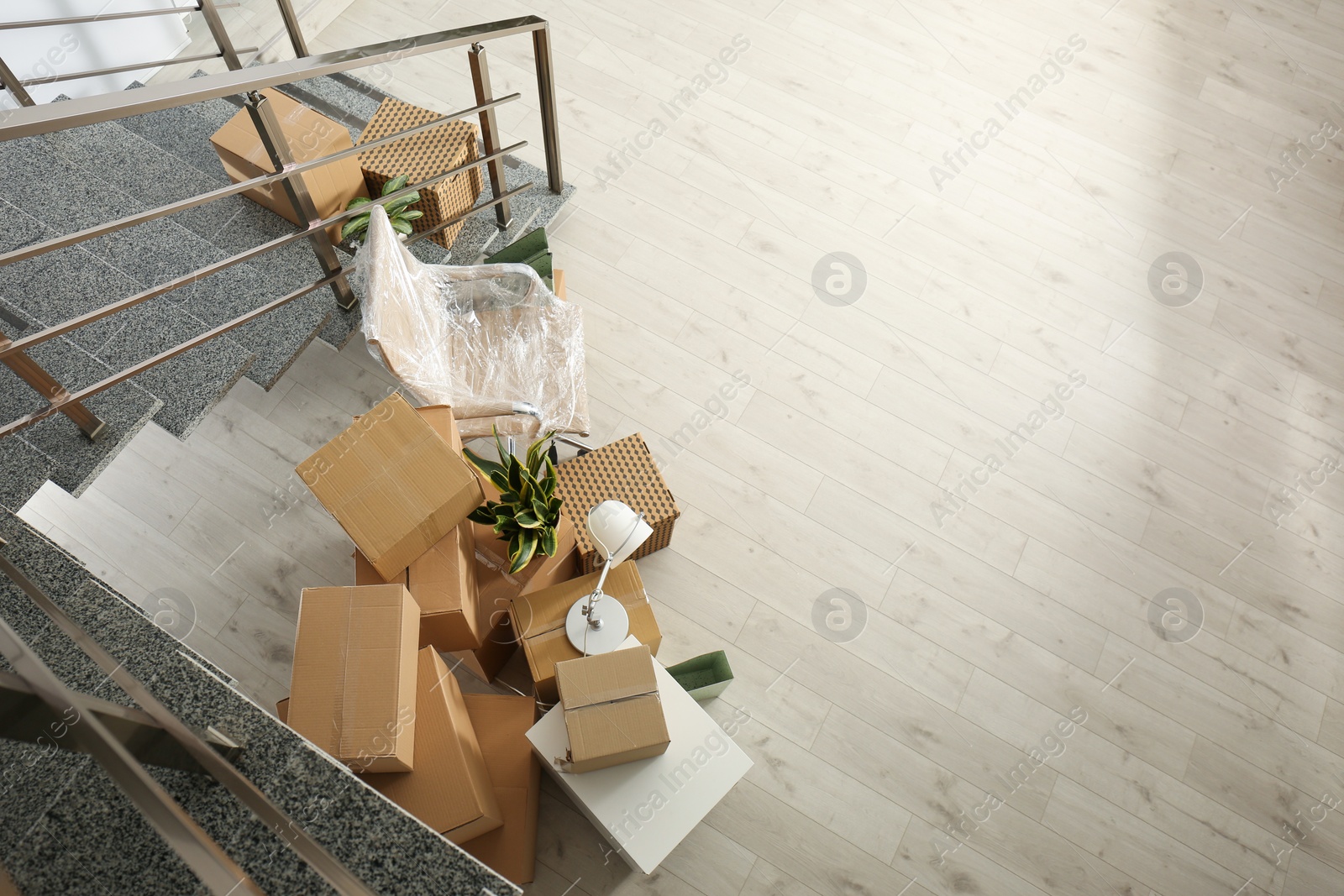 Photo of Cardboard boxes and packed chair near stairs in office, above view with space for text. Moving day