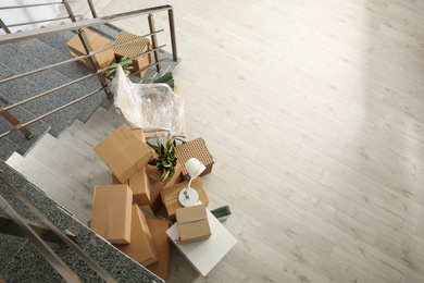 Photo of Cardboard boxes and packed chair near stairs in office, above view with space for text. Moving day