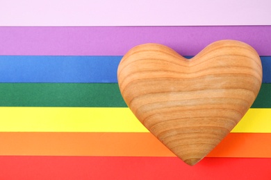 Photo of Wooden heart on rainbow background, top view. Gay symbol