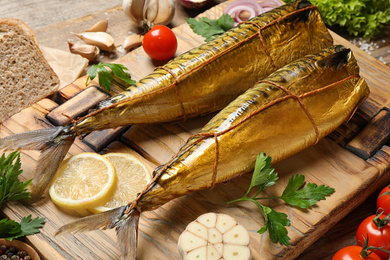 Tasty smoked fish served on wooden table