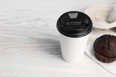 Paper cup and muffin on white wooden table, space for text. Coffee to go