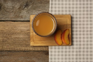 Glass of tasty peach juice and fresh fruit on wooden table, top view