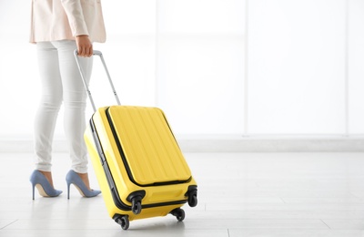 Businesswoman with yellow travel suitcase in airport. Space for text
