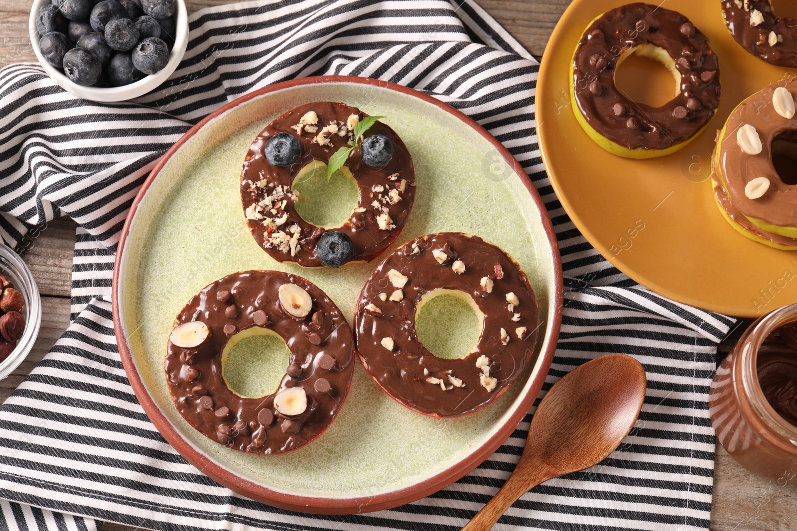 Photo of Fresh apples with nut butter, hazelnuts, blueberries and chocolate chips on table, flat lay