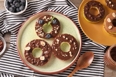 Photo of Fresh apples with nut butter, hazelnuts, blueberries and chocolate chips on table, flat lay