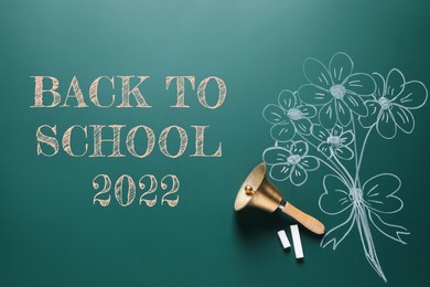 Image of Back to school 2022. Golden bell, pieces of chalk and drawn flowers on greenboard, flat lay