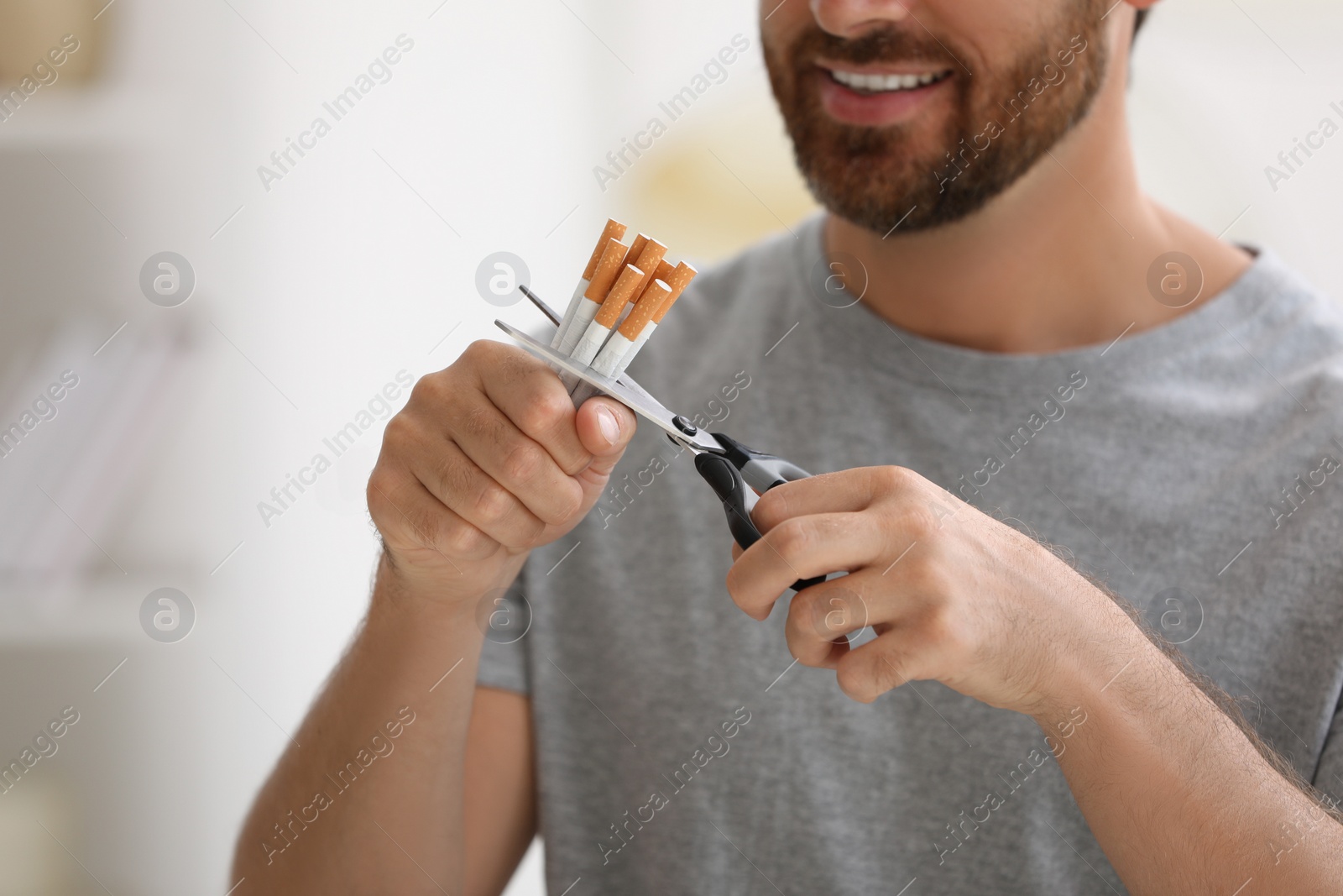 Photo of Stop smoking concept. Man cutting cigarettes on blurred background, closeup