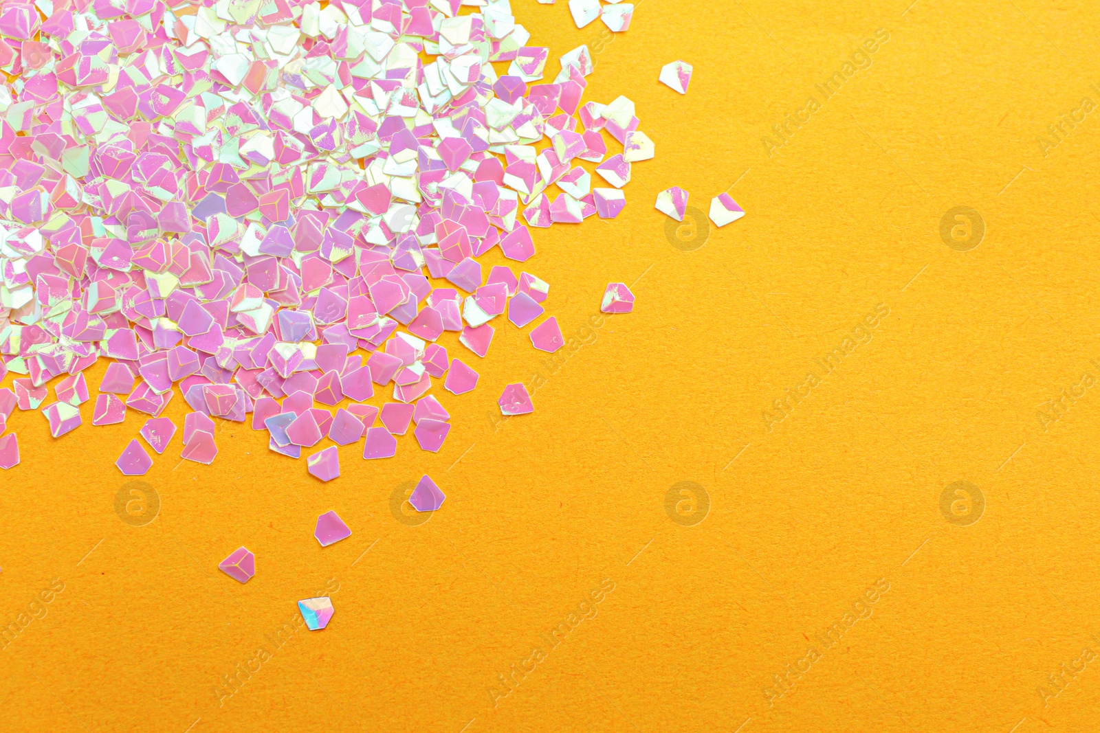 Photo of Shiny bright pink glitter on yellow background, flat lay. Space for text