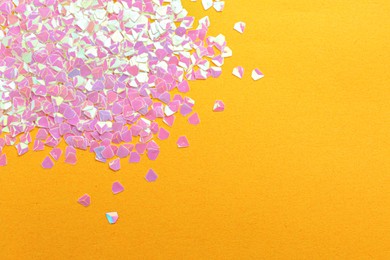 Photo of Shiny bright pink glitter on yellow background, flat lay. Space for text