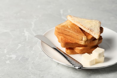 Photo of Tasty toasts with butter served on grey marble table. Space for text