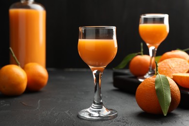 Tasty tangerine liqueur and fresh fruits on black textured table