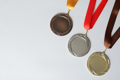 Gold, silver and bronze medals on white background, flat lay. Space for design